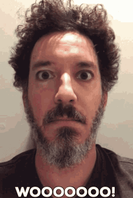 a man with curly hair and a beard is making a surprised face with the words woooooo on the bottom