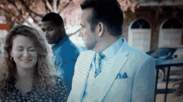 a man in a white suit and tie is standing next to a woman