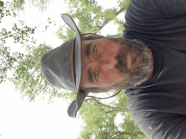 a man with a beard wearing a cowboy hat and a black shirt