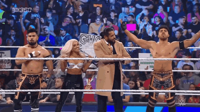a group of wrestlers are standing in a wrestling ring with a crowd behind them and a sign that says gwc