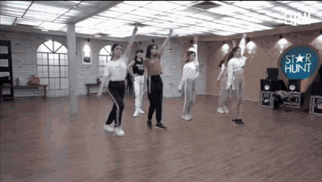 a group of women are dancing in a room with a star hunt logo in the background