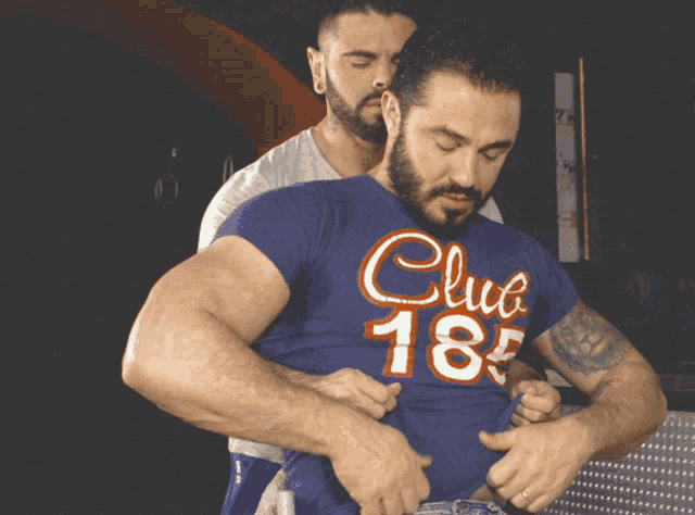two men are standing next to each other and one has a shirt that says club 185
