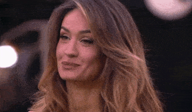 a close up of a woman 's face with long hair making a funny face .