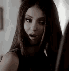 a woman with long hair is looking at herself in a mirror .