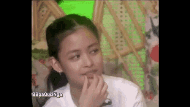 a young girl is sitting down with her hand on her chin .