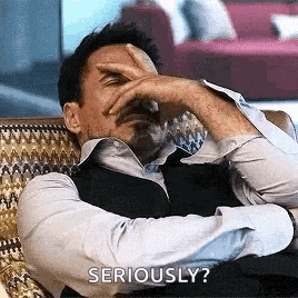 a man is sitting in a chair with his hand on his forehead and the words `` seriously ? ''