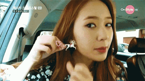 a woman in a car is wearing a pair of earrings that have a horse on them