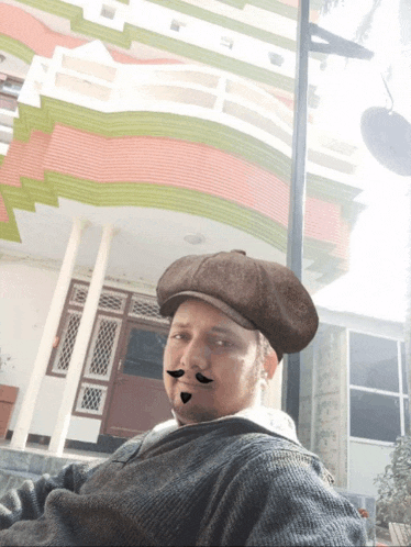 a man wearing a hat with a fake mustache is sitting in front of a building