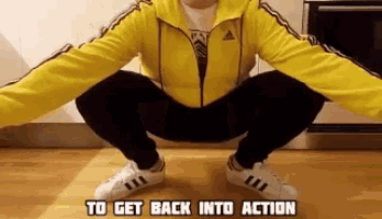 a person in a yellow adidas jacket squatting down