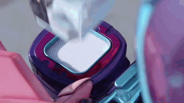 a person is cleaning a purple and blue appliance
