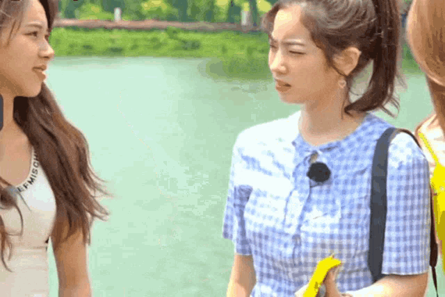 a woman in a blue plaid shirt is talking to two other women