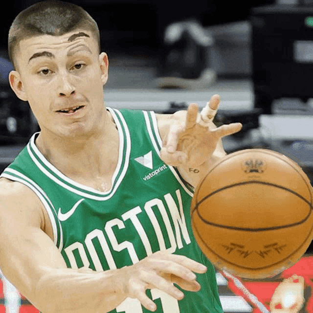 a man wearing a green boston jersey holds a basketball
