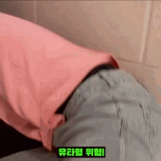 a person wearing a pink shirt and blue jeans is sitting in a bathroom .