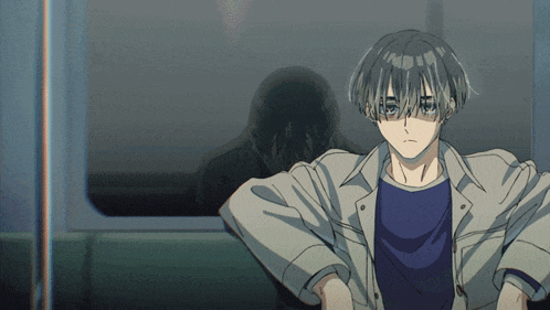a boy with blue eyes is sitting in a dark room with his hands on his hips