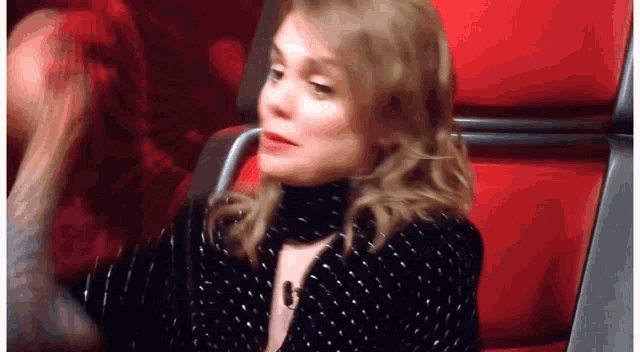 a woman in a black and white polka dot dress is sitting in a red seat .