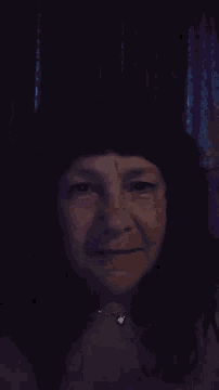 a close up of a woman 's face in the dark with a necklace on .