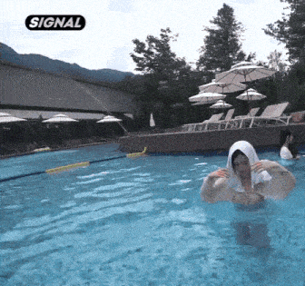 a woman with a towel on her head is swimming in a pool with umbrellas .