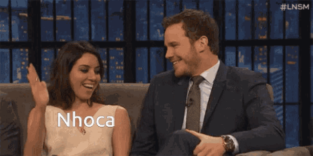 a man and a woman sitting on a couch with the word nhoca written on the bottom