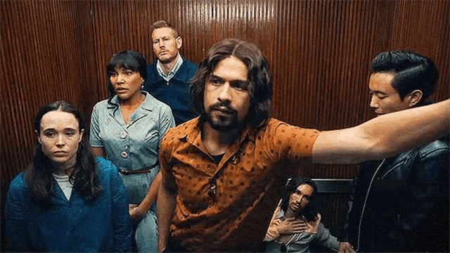a group of people are standing in an elevator and looking at the camera .