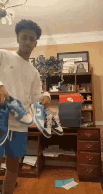 a young man is holding a pair of nike shoes in his hands