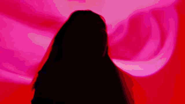 a woman with long black hair is standing in front of a red light .