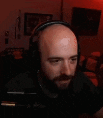 a bald man with a beard is wearing headphones while sitting in front of a computer .