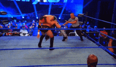 two wrestlers are fighting in a ring with a referee