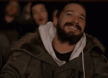 a man with a beard is laughing while watching a movie at a theater .