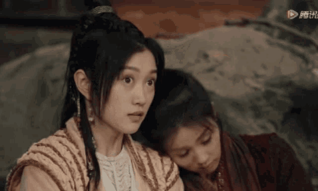 a woman sitting next to another woman with chinese writing on the bottom right
