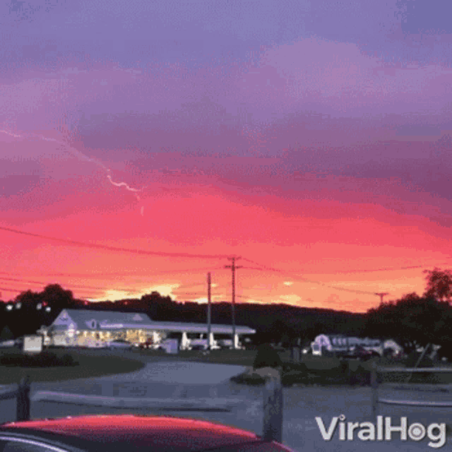a car is parked in front of a red and purple sunset with the words viralhog on the bottom right