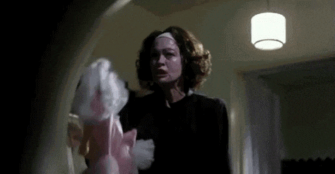 a woman in a black dress is holding a pink stuffed animal .