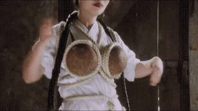 a woman is tied up with a rope and has a large bra on .