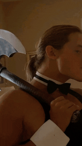 a man wearing a choker and bow tie holds a bottle of whiskey