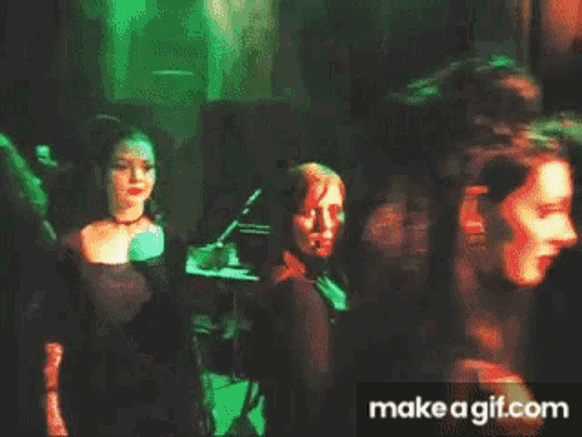 a man in a suit and tie is dancing with a woman in a black dress in a crowded room .
