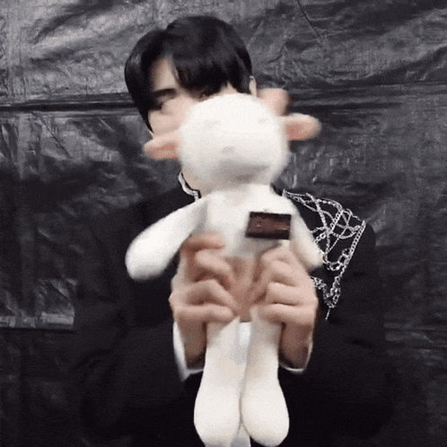 a man is holding a white stuffed animal with a sticker on it .