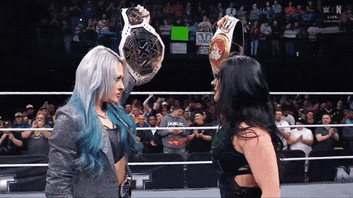 two women in a wrestling ring with one holding a belt that says champion