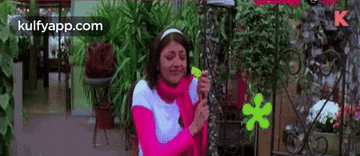 a woman is holding a green flower in her hands in a garden .