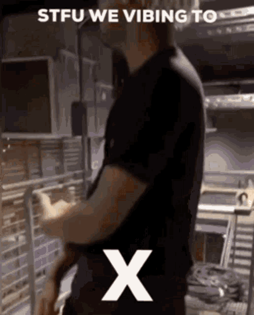 a man in a black shirt is standing in front of a white x