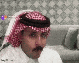 a man with a mustache is wearing a head scarf and sitting on a couch
