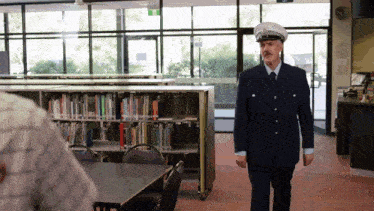 a man in a police uniform stands in front of a bookshelf