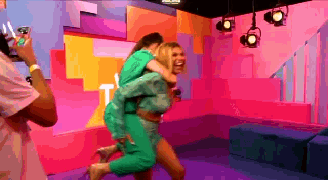 a woman in a green dress is carrying another woman on her back in a colorful room .