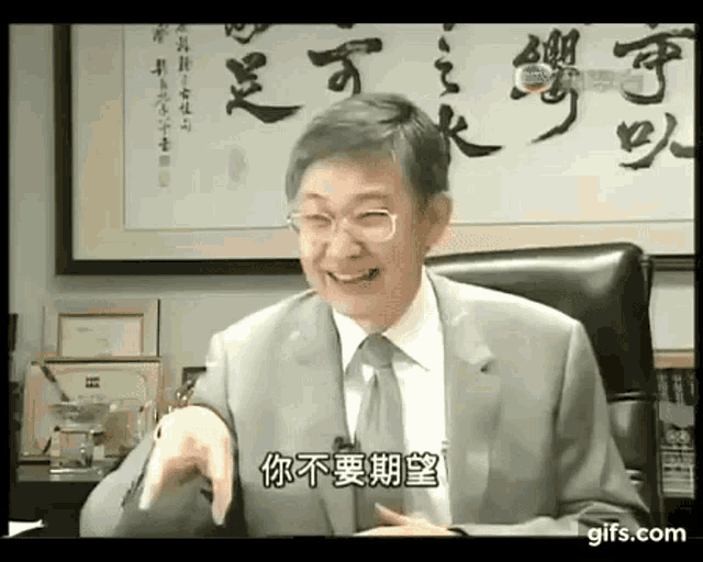 a man in a suit and tie is smiling and pointing at the camera .