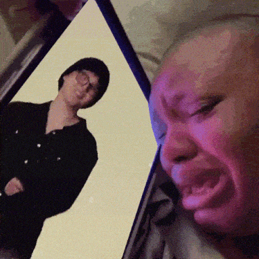 a person is crying while looking at a picture of a man