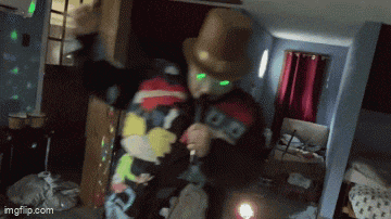 a man wearing a top hat and a jacket with the letter b on it is dancing in a room .