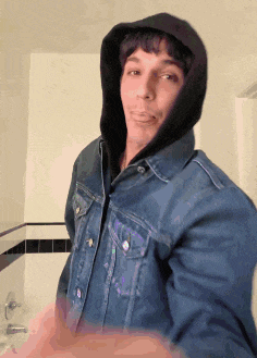 a man wearing a denim jacket with a black hoodie on his head