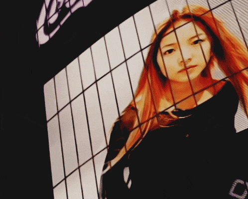 a woman with red hair is behind bars with a reflection of her face