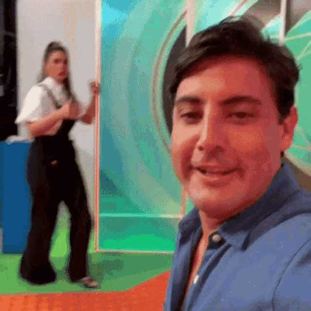 a man is taking a selfie with a woman in the background