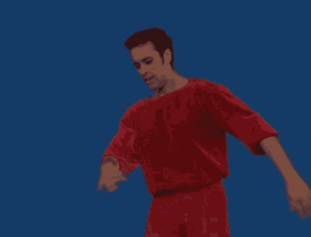 a man in a red shirt is raising his hand in the air