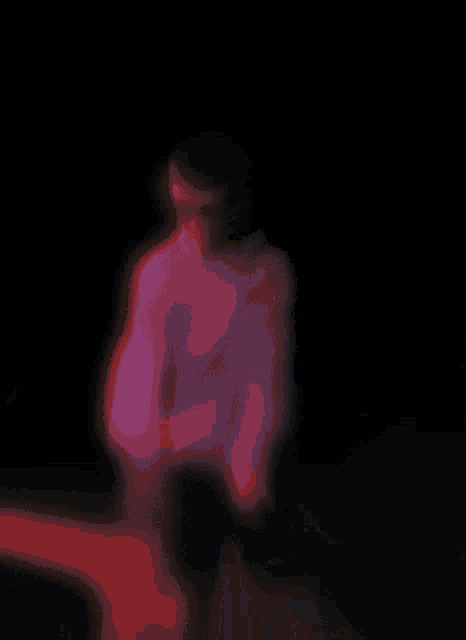 a person 's face is visible in a dark room with purple and pink lights