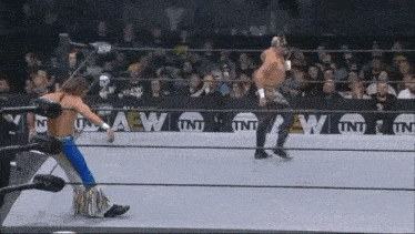 two wrestlers are fighting in a wrestling ring with a crowd watching .